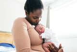 Woman holding a newborn baby in a bedroom setting